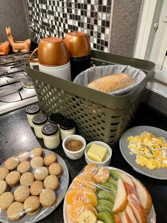 Desayuno casero con pan, medialunas, frutas, huevos y termos de café